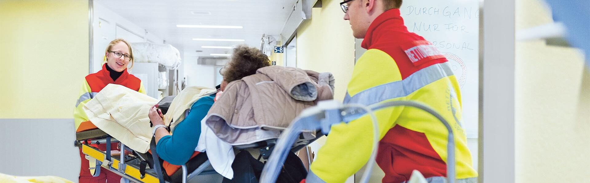 Zwei Rettungssanitaeter transportieren Patient auf Barre